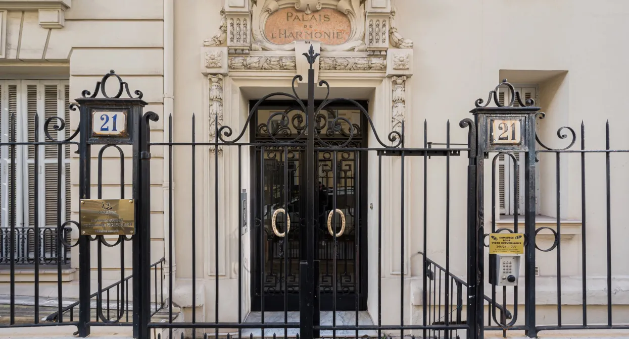 Вход в элитный жилой дом с декоративными элементами и металлическими воротами.